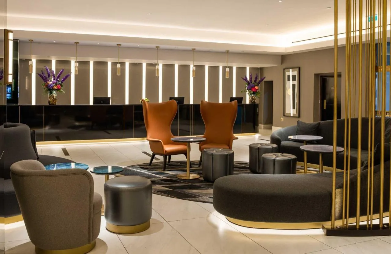 a lobby with chairs and tables and a piano at Strand Palace in London