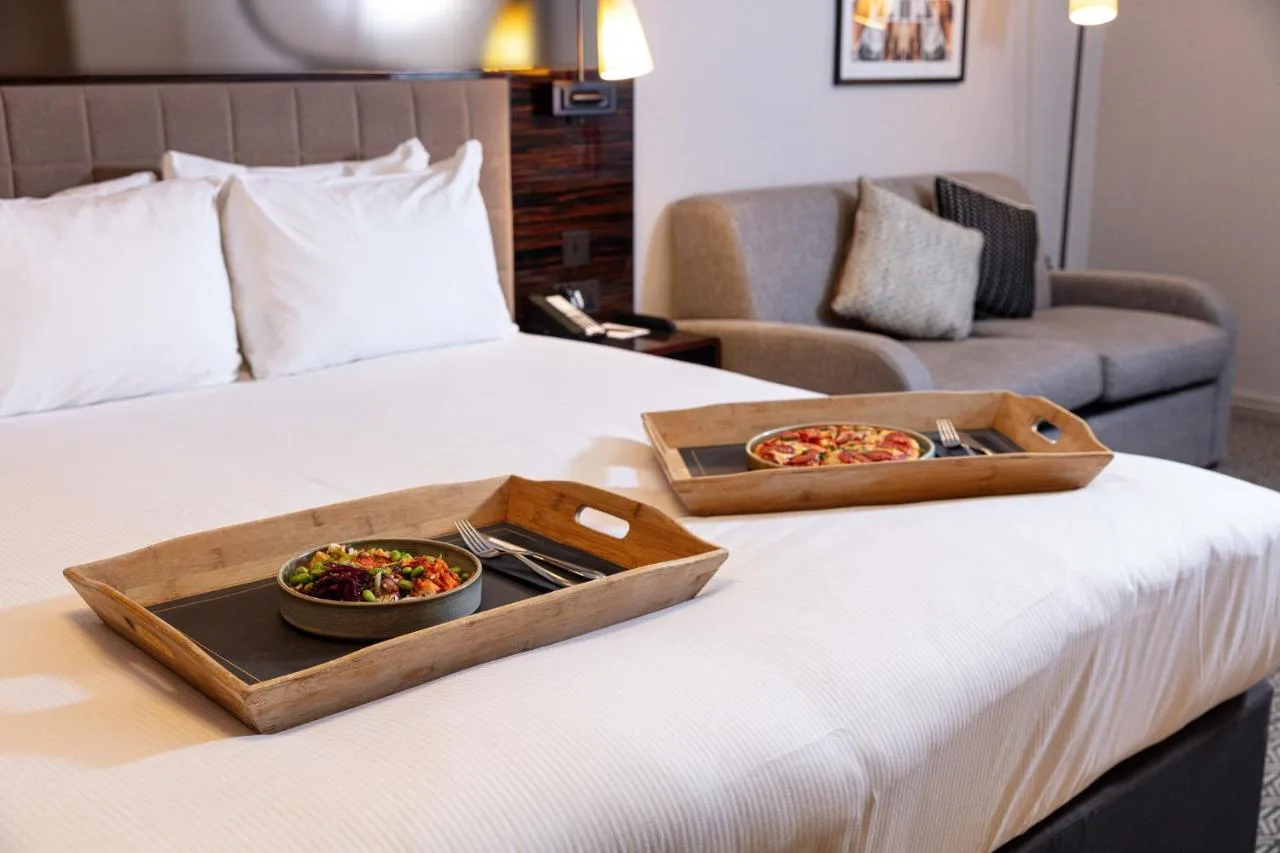 a tray of food on a bed with a plate of pizza at Strand Palace in London